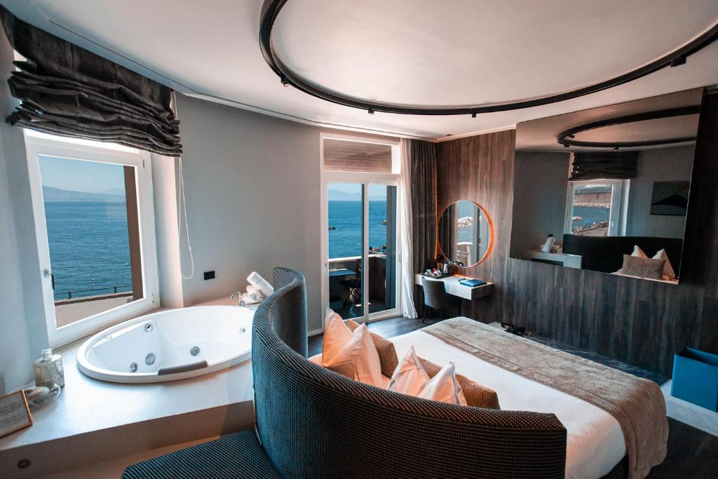 ein Schlafzimmer mit einer Badewanne und einem Bett mit einem Stuhl in der Unterkunft Relais sul Mare Boutique Hotel in Neapel