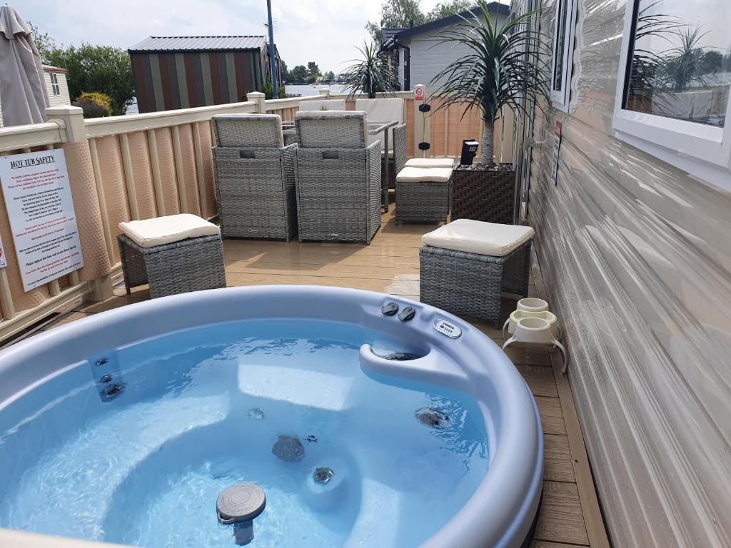 塔特舍爾的住宿－Relaxing Breaks with Hot tub at Tattershal lakes 3 Bedroom，阳台设有按摩浴缸和椅子