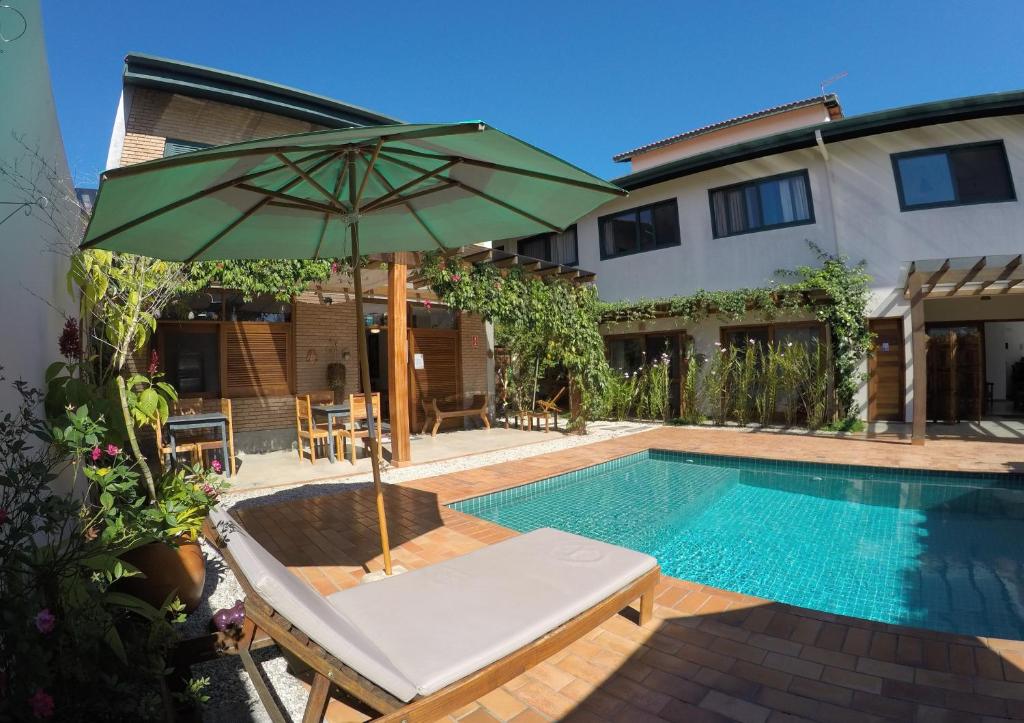 - une piscine avec un parasol, une chaise et une table avec un parasol dans l'établissement Nai'a Suites, à Ubatuba