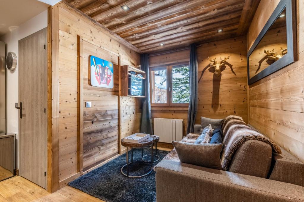 - un salon avec des murs en bois et un canapé dans l'établissement Flocon des Neiges, à Praz-sur-Arly