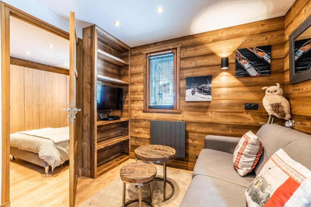 Habitación con paredes de madera, sofá y cama. en Le Hameau des Neiges, en Praz-sur-Arly