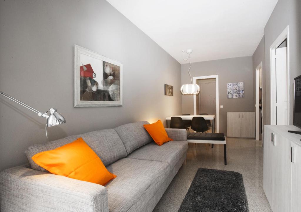 sala de estar con sofá gris y almohadas de color naranja en Bcn Sagrada Familia Apartments, en Barcelona