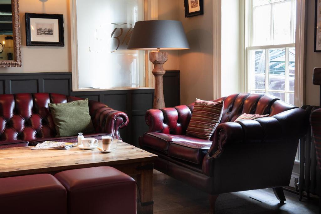 a living room with two leather couches and a table at Broom Hall Inn in Stratford-upon-Avon