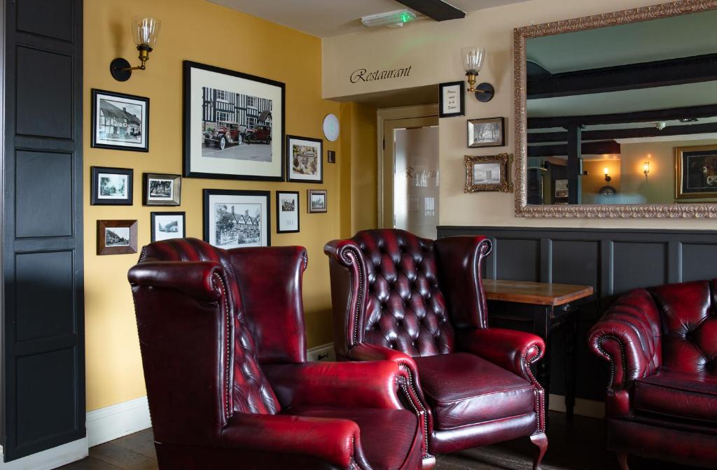 a waiting room with red leather chairs and a mirror at Broom Hall Inn in Stratford-upon-Avon