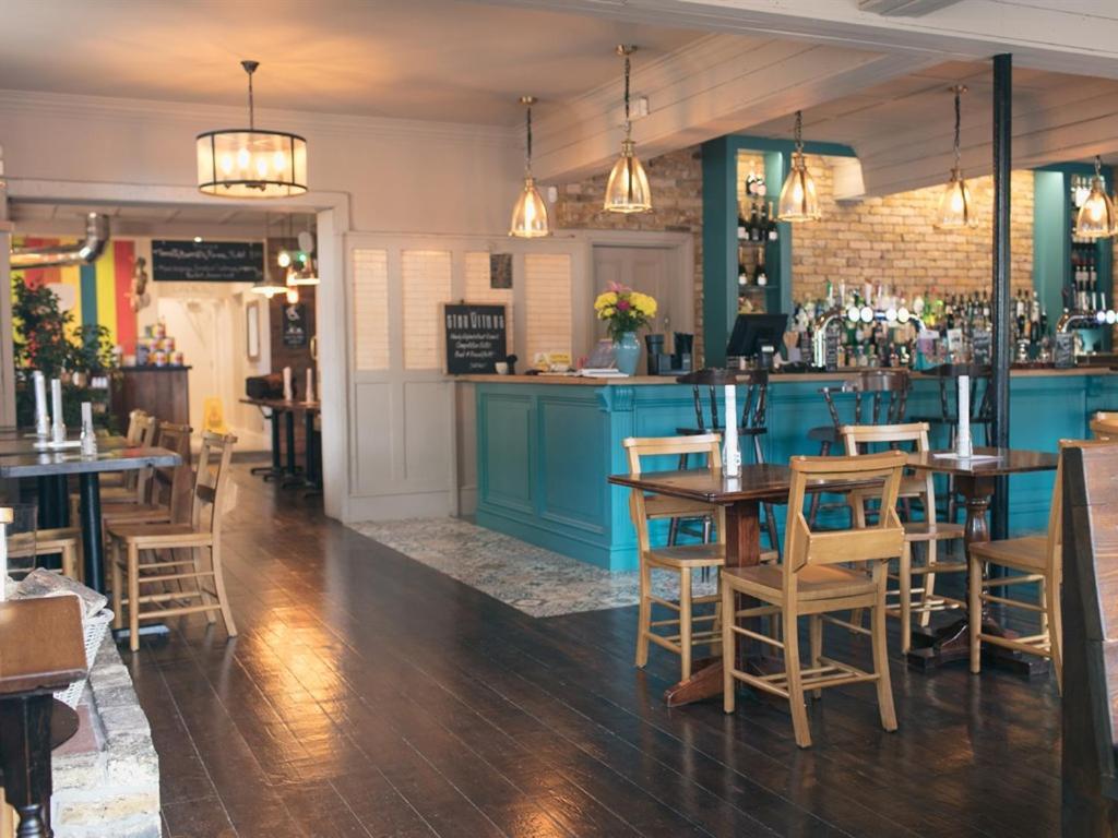 um restaurante com mesas e cadeiras e um bar em The Green W7 em Londres