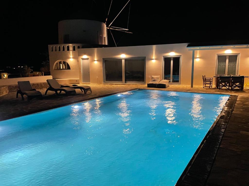 a large blue swimming pool at night at Windmill House Antiparos in Soros