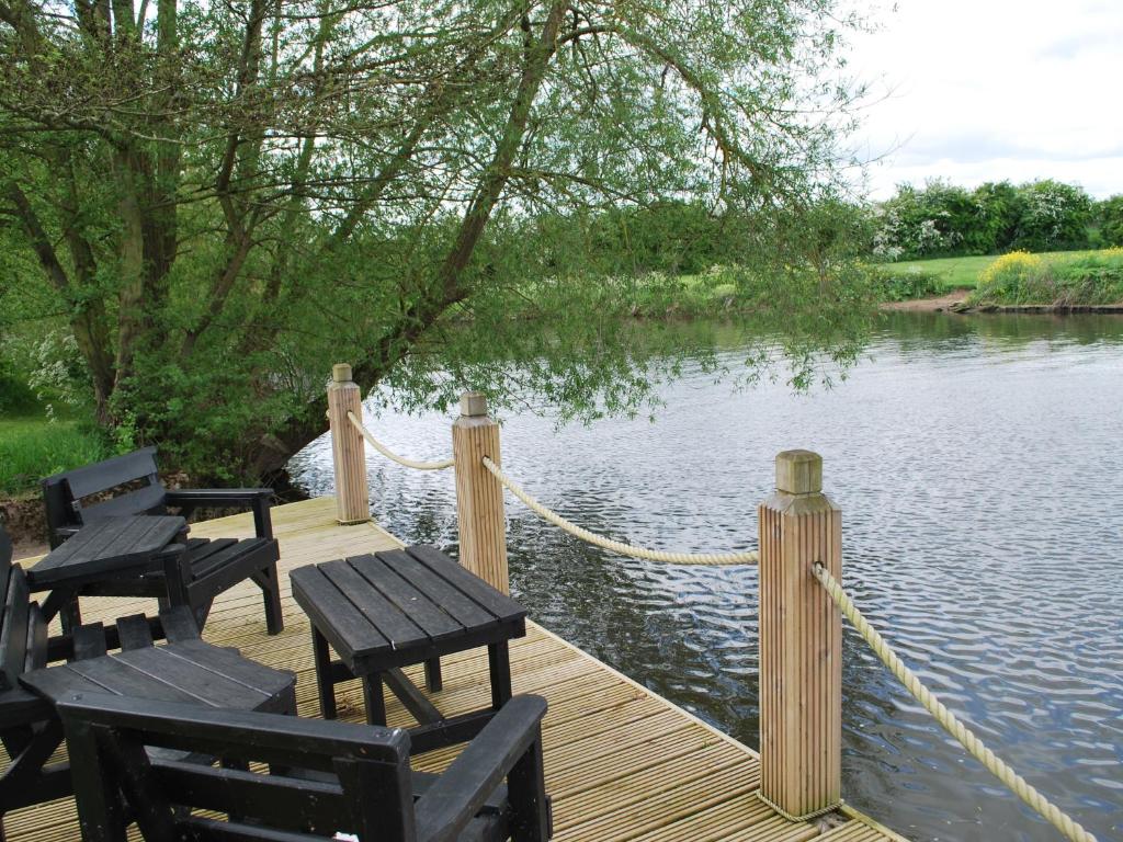 a dock with picnic tables and chairs on the water at The Waters Edge Guest House in Stratford-upon-Avon