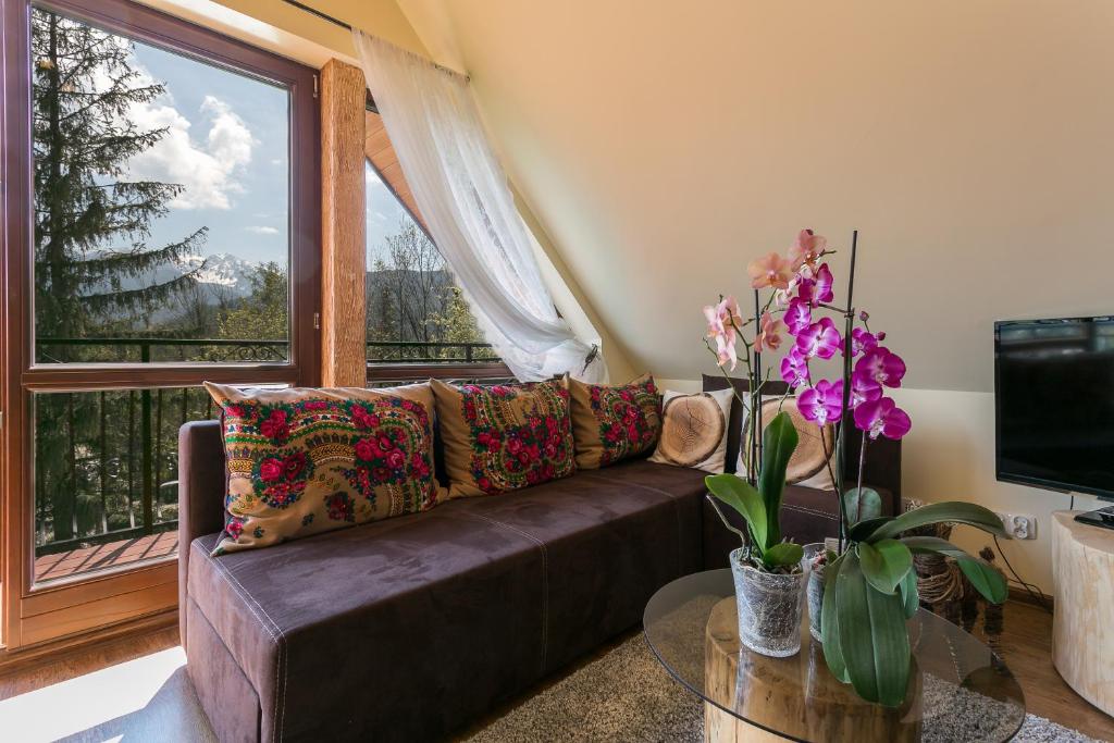 a living room with a couch and a large window at VIP Apartamenty Widokowe in Zakopane