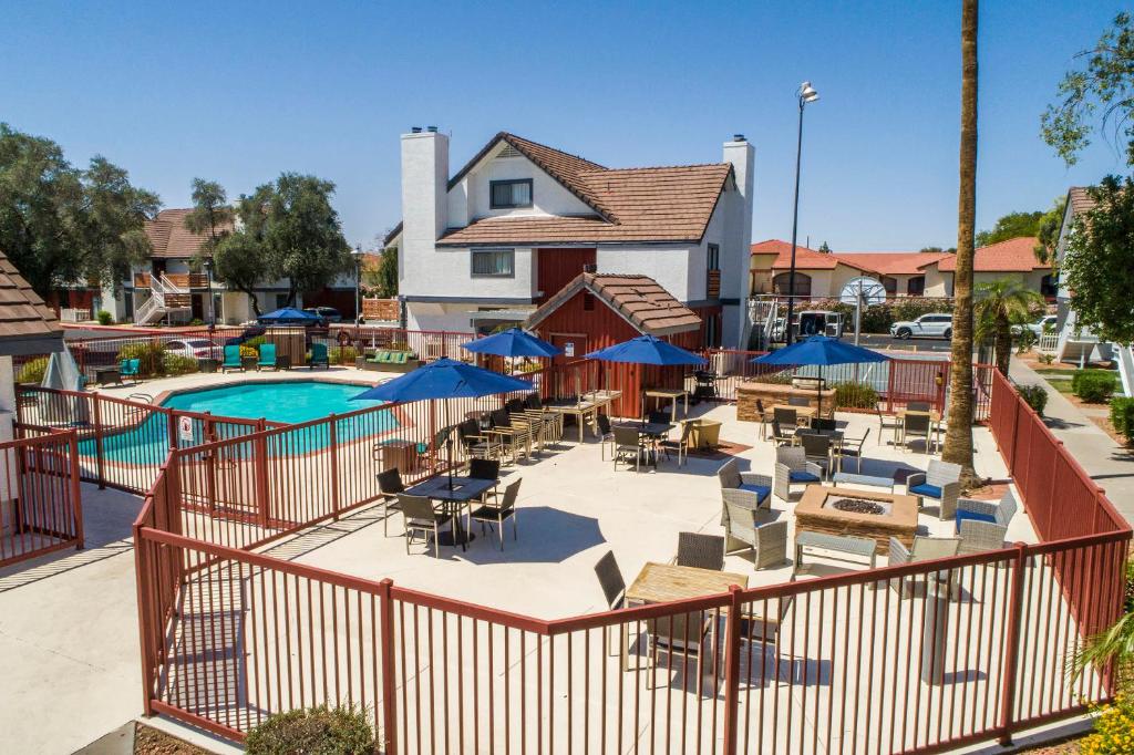 uma piscina com mesas, cadeiras e guarda-sóis azuis em Metro PHX Upstairs 2bd sleeps 6 heated pool NO PETS ALLOWED em Phoenix