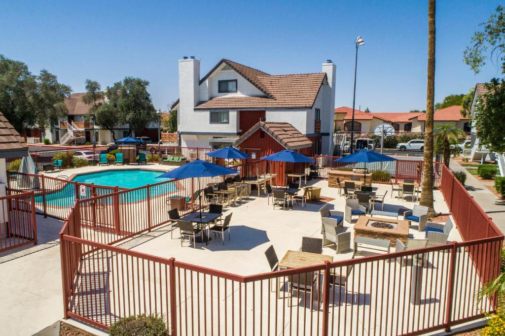 a pool with tables and chairs and blue umbrellas at Metro PHX Upstairs 2bd sleeps 6 heated pool NO PETS ALLOWED in Phoenix
