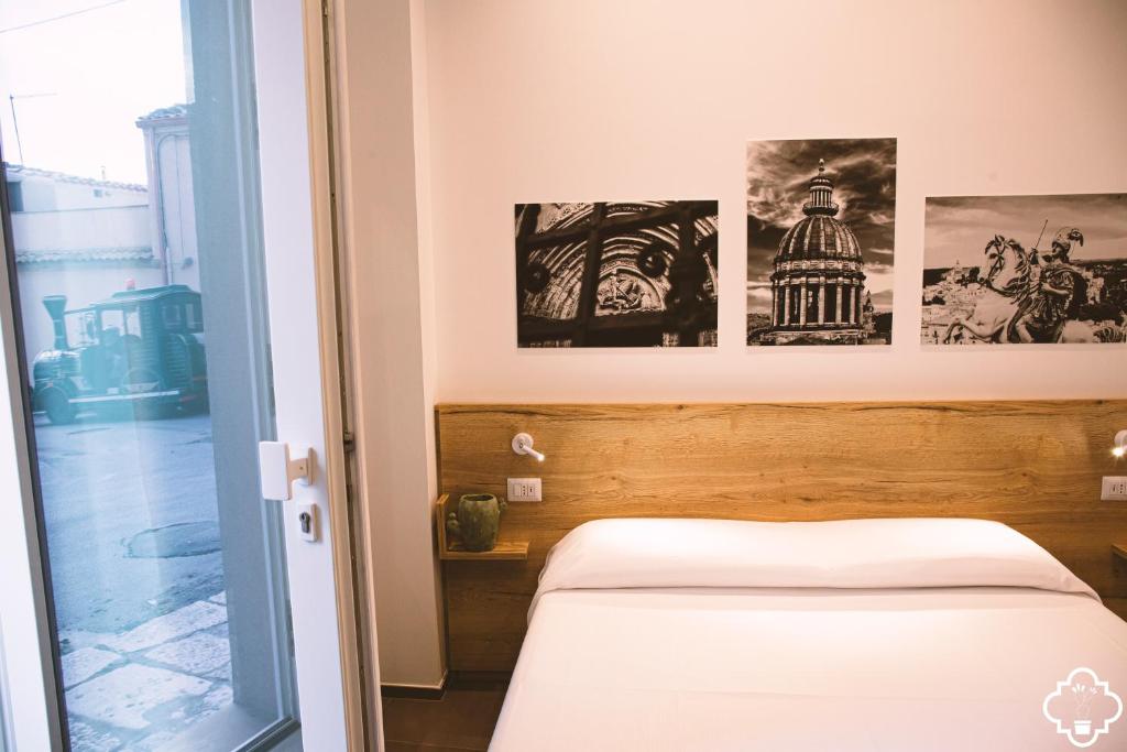 a bedroom with a bed and some pictures on the wall at Fico - Finestra Contemporanea in Ragusa