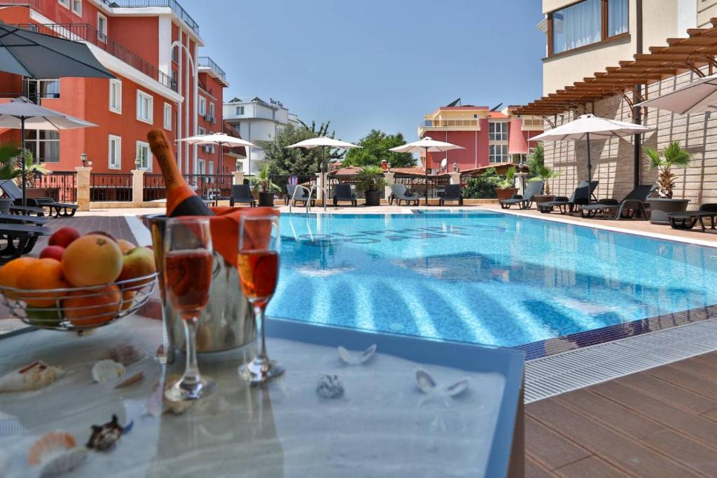 a table with drinks and a bowl of fruit next to a swimming pool at VIP CLUB Dolphin Coast in Sunny Beach