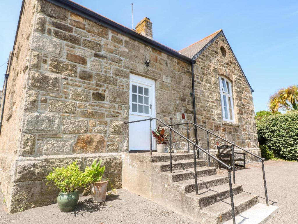 a stone building with a white door and stairs at The Cottage in Penzance