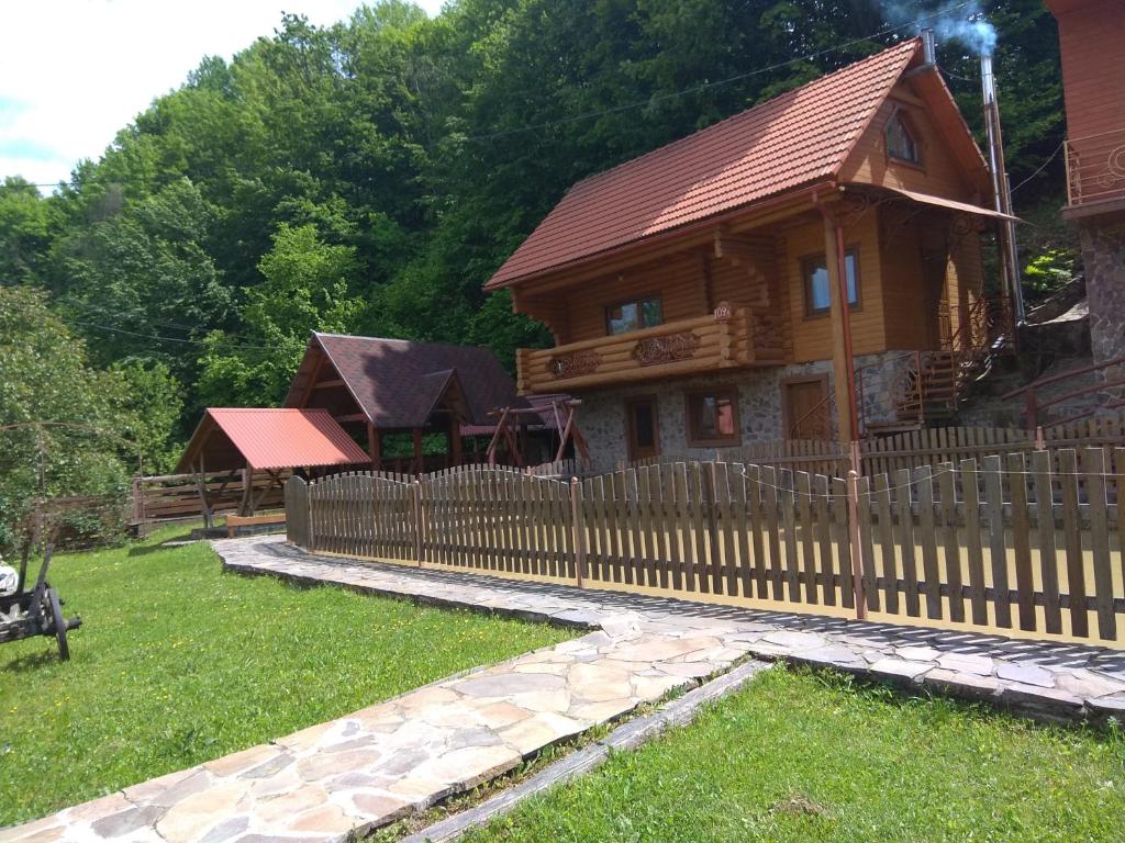 a wooden fence in front of a log cabin at Садиба у Льотчика in Polyana