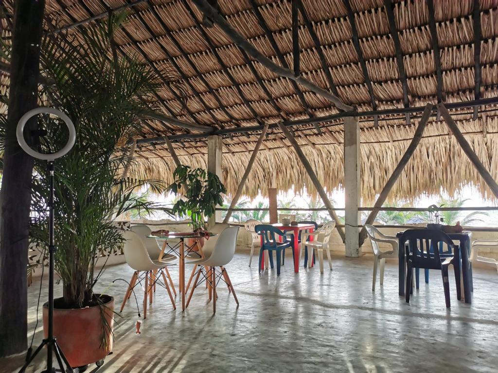 un restaurante con sillas, mesas y techo de paja en Casa el Muelle, en Coveñas