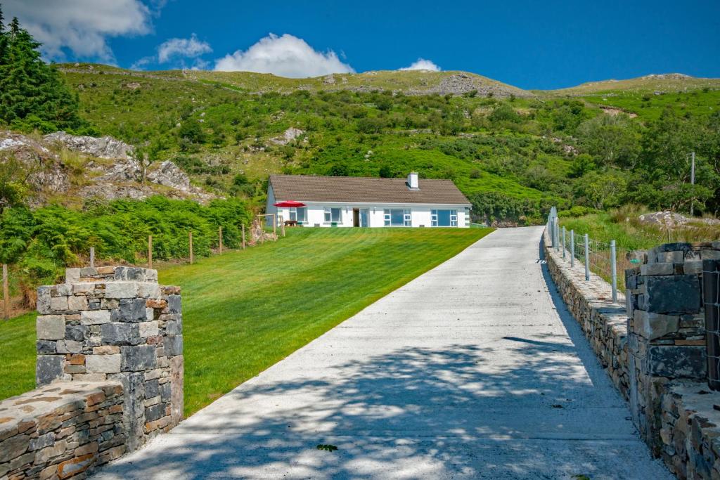 eine Auffahrt zu einem weißen Haus mit einem Berg in der Unterkunft Cottage 390 - Maam in Claggan