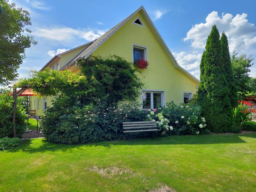 una casa amarilla con un banco en un patio en Ferienwohnung Lotte en Felgentreu