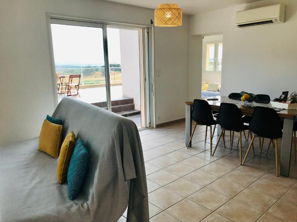 PoggiにあるBel appartement dans villa à la campagne proche d’Ajaccioのソファとテーブルと椅子のあるリビングルーム