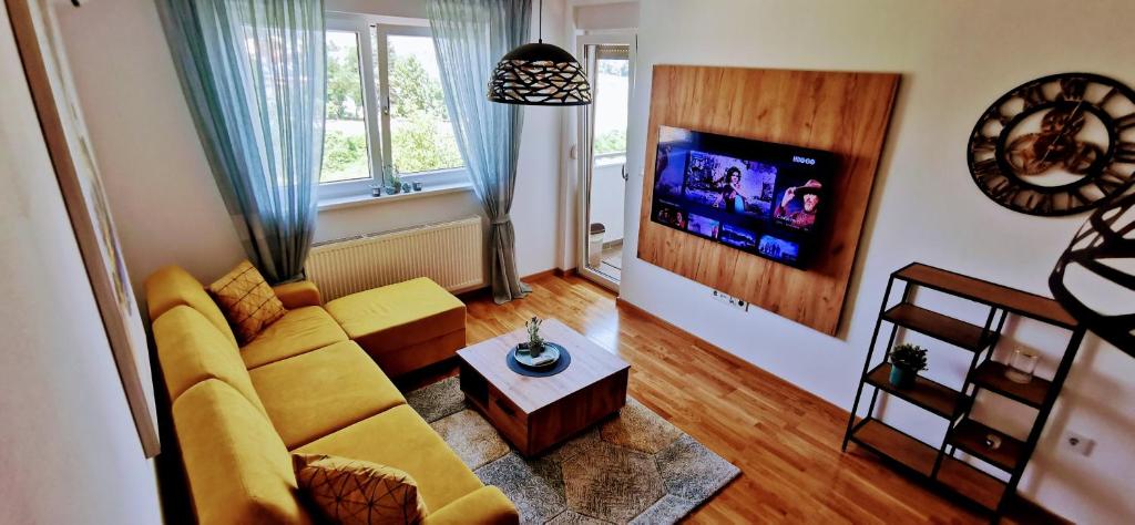sala de estar con sofá amarillo y TV en Apartman VARENICA, en Doboj