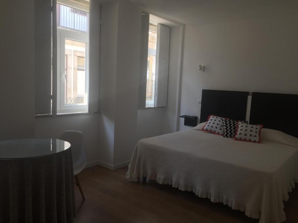 a bedroom with a bed and two windows at Douro - A Casinha da Ana in Vila Real