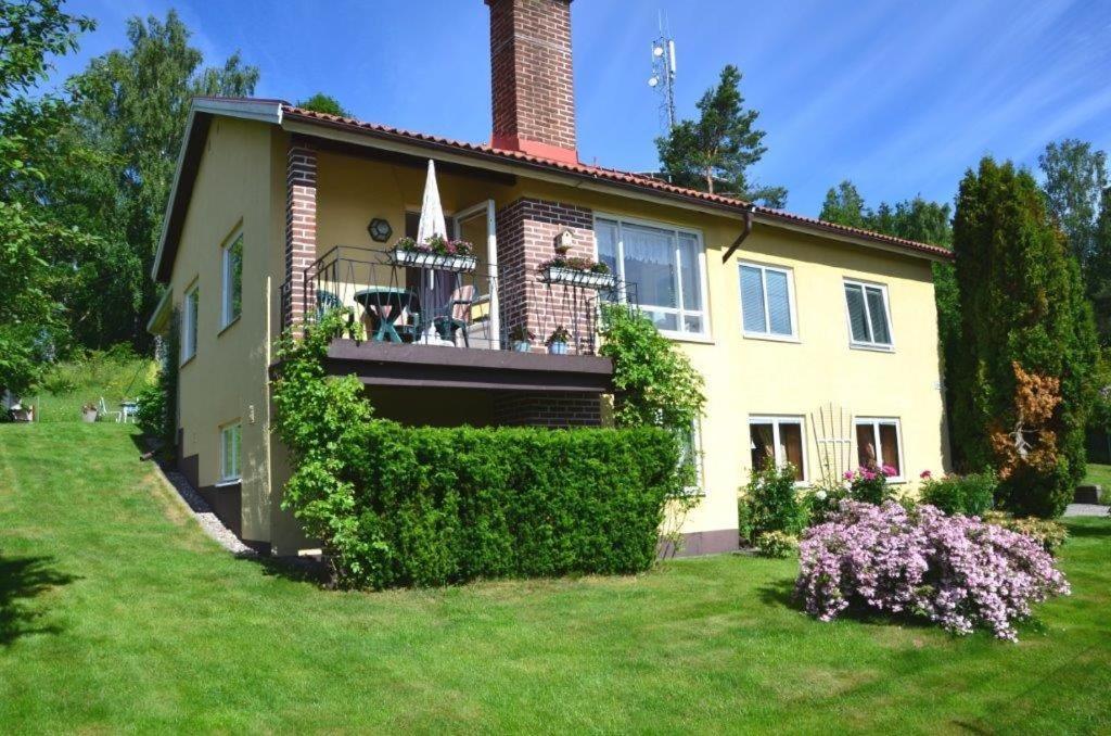 ein gelbes Haus mit einem Balkon und Büschen in der Unterkunft Apartments "Ecohouse" nearby Håverud Dalsland Sweden in Åsensbruk