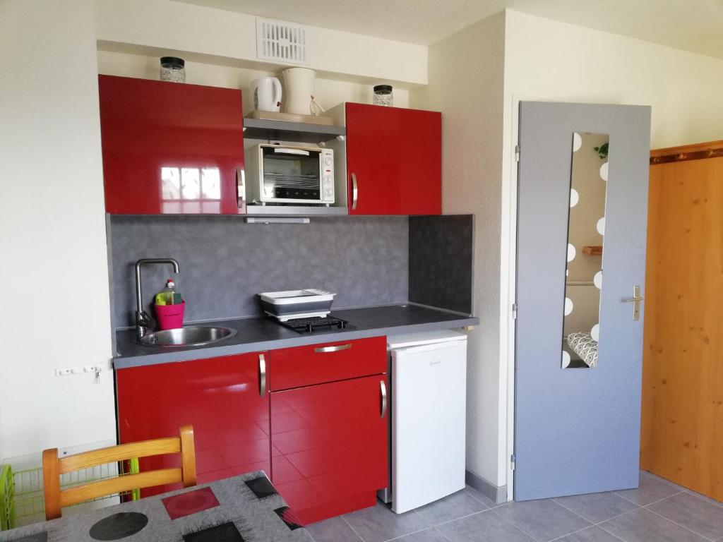 a kitchen with red cabinets and a sink at Courseulla in Courseulles-sur-Mer