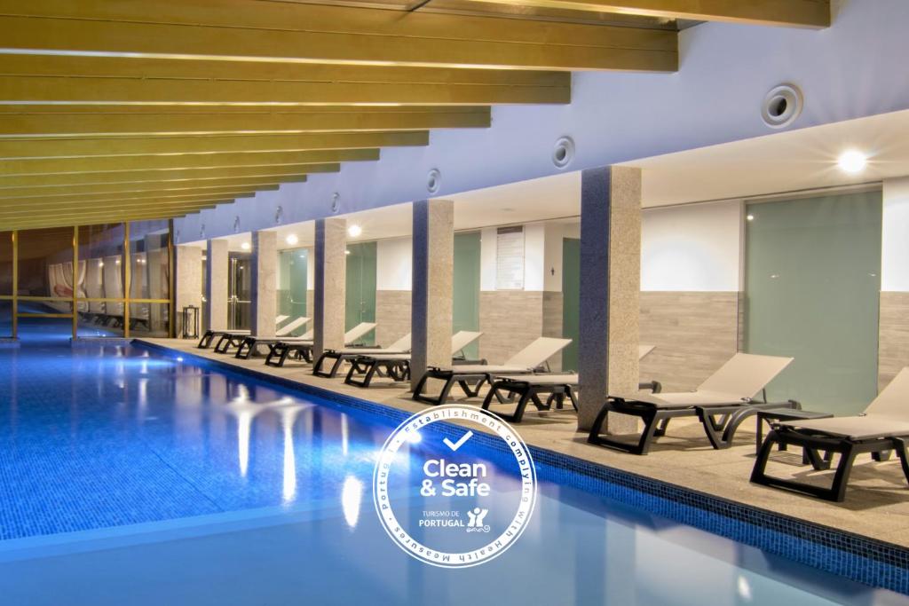 - une piscine avec des chaises et un panneau indiquant propreté et sécurité dans l'établissement Luna Hotel Serra da Estrela, à Covilhã