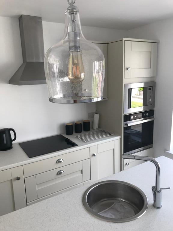 a kitchen with a sink and a large light fixture at Unique Belfast Stay in Belfast