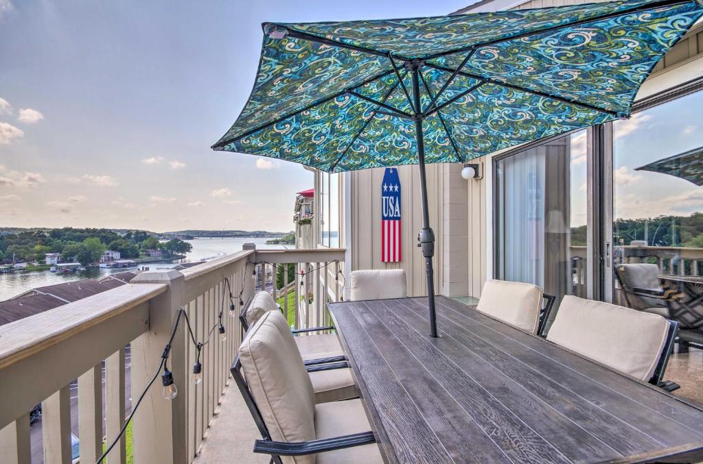 a wooden table with an umbrella on a balcony at Osage Beach Condo with Shared Pool and Lake Views! in Osage Beach