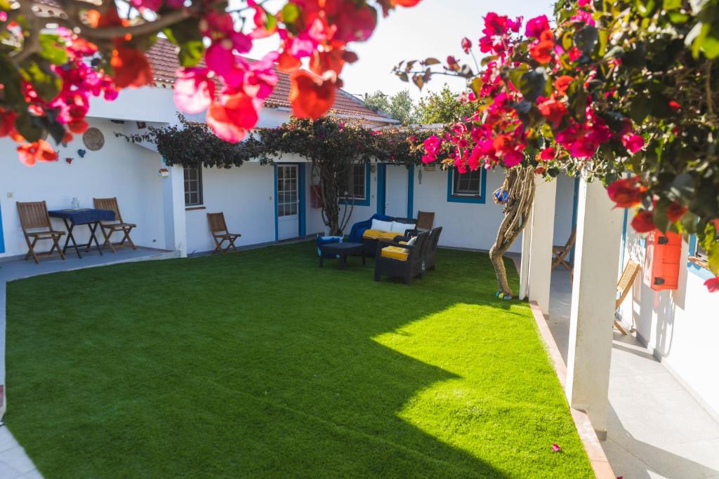 un patio con césped verde y flores rosas en Villa Berlenga en Atouguia da Baleia