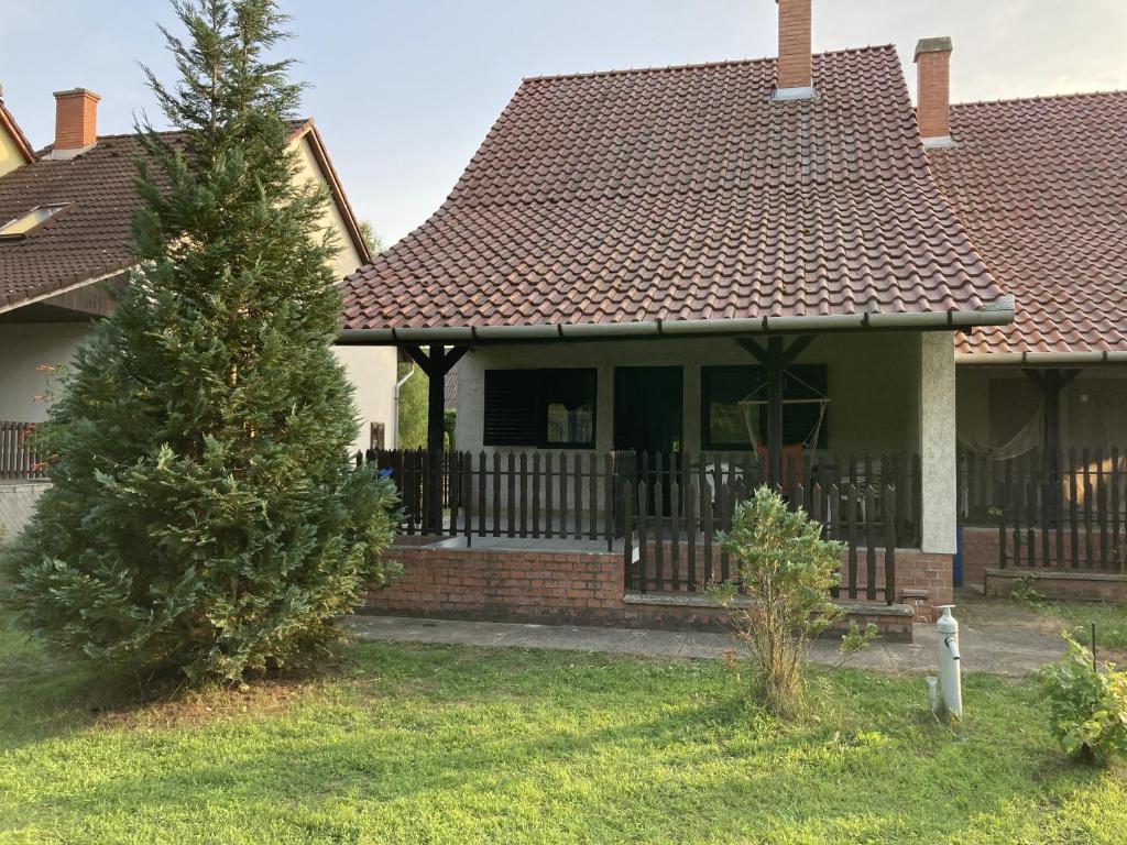 a house with a fence and a tree in the yard at Zöldike Vendégház in Tiszafüred
