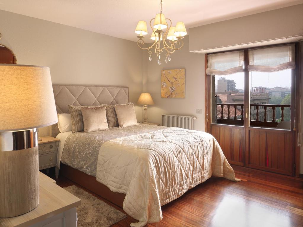 - une chambre avec un lit, un lustre et une fenêtre dans l'établissement El Mirador de Begona, à Gijón