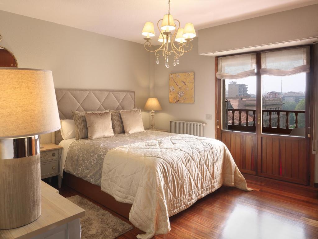 una camera da letto con un letto con un lampadario a braccio e una finestra di El Mirador de Begoña - VUT-606-AS a Gijón