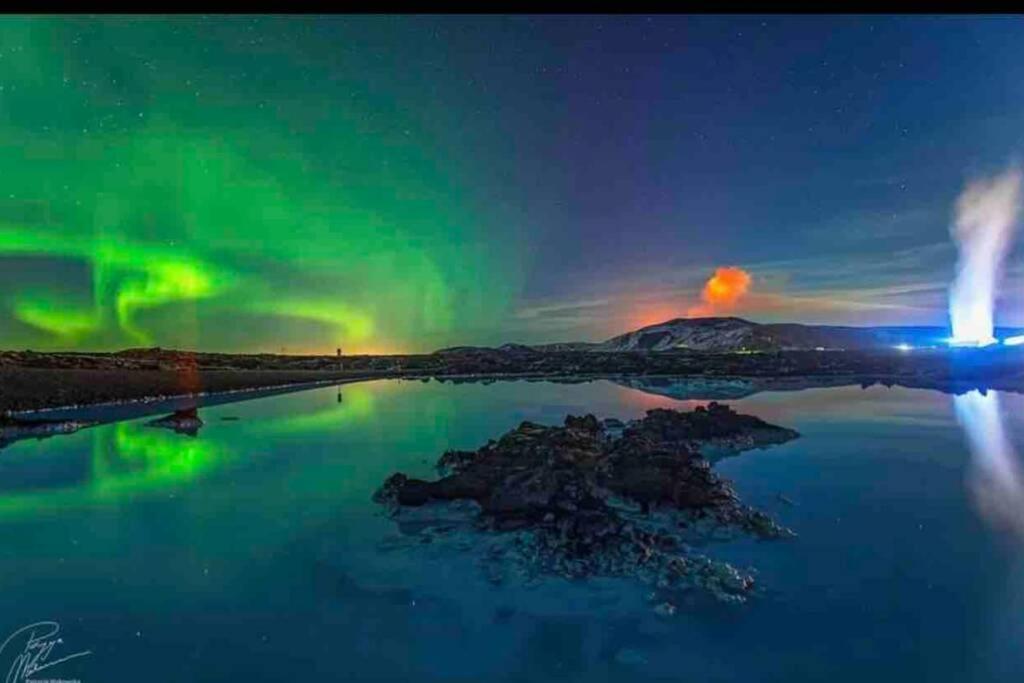 an aurora over a body of water at night at Private studio apartment near the airport in Ytri-Njarðvík
