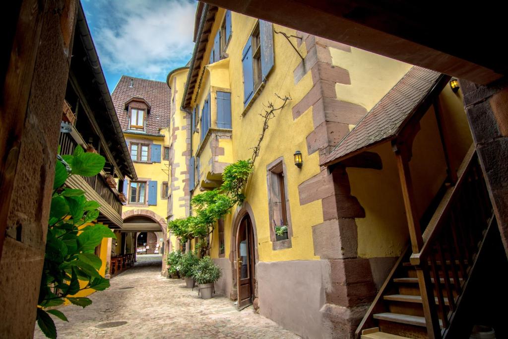 an alley in an old town with yellow buildings at Hôtel De La Couronne in Riquewihr