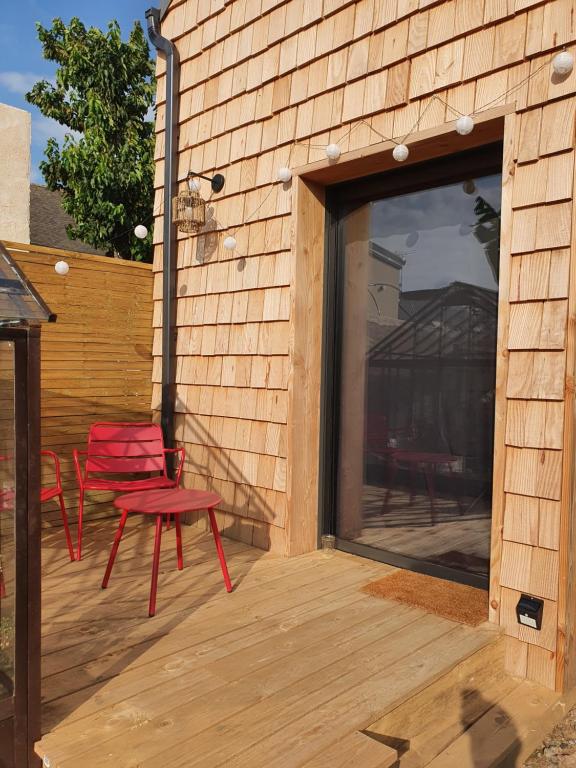 a patio with two red chairs and a large window at Tiny House Cosy 2 - Angers Green Lodge in Angers