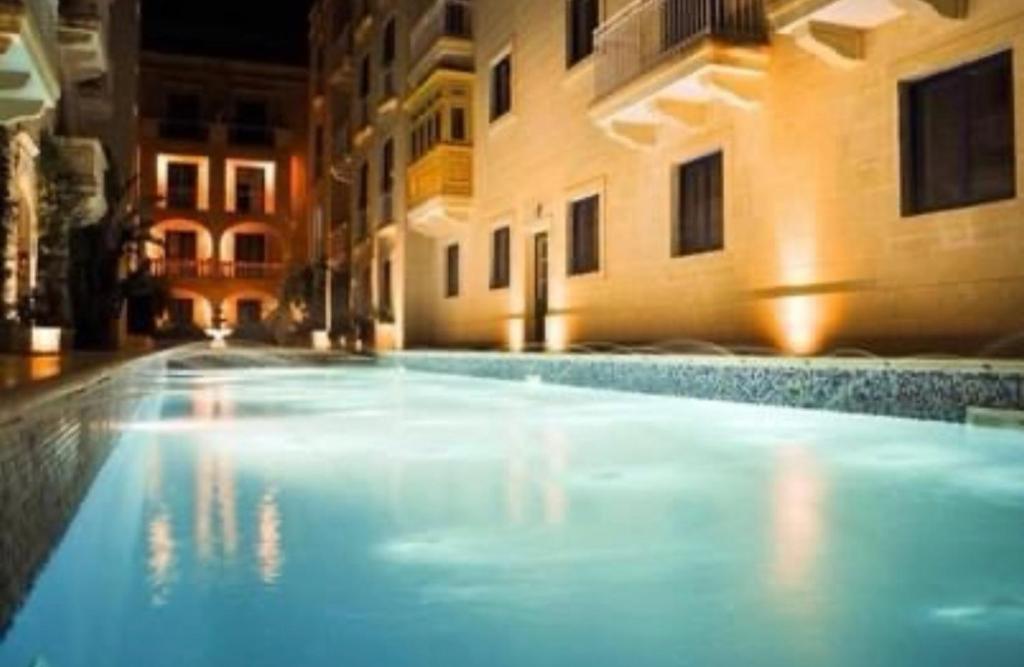 - une grande piscine dans un bâtiment la nuit dans l'établissement Ix Xaluppa J6 Apartment, à Għajnsielem
