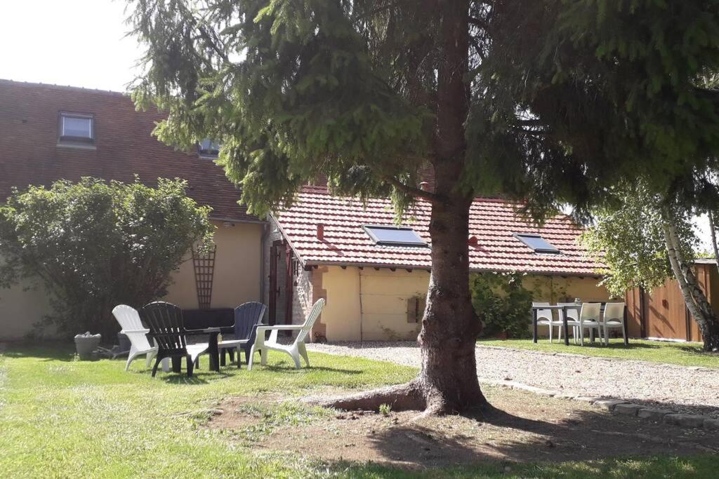 a table and chairs under a tree next to a house at Villa Sauna Tout Confort Pleine Campagne in Ladon