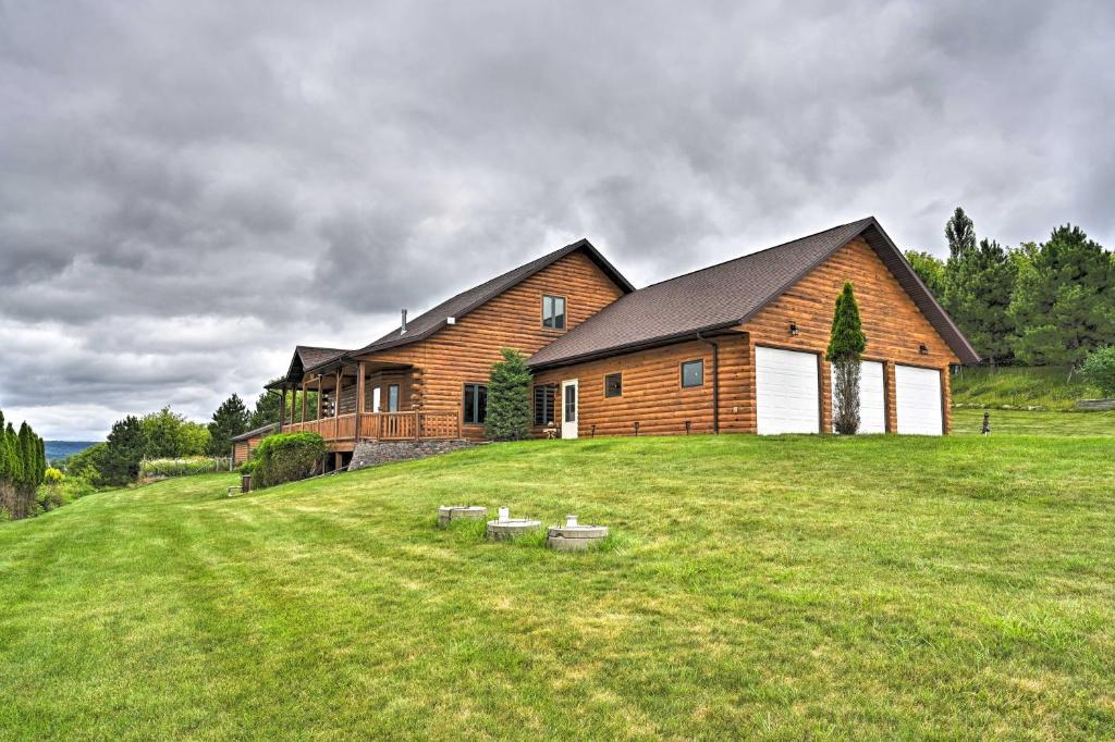 a large wooden house on a grassy field at Hillside Hideaway with Hot Tub and Heated Patio! in Baraboo