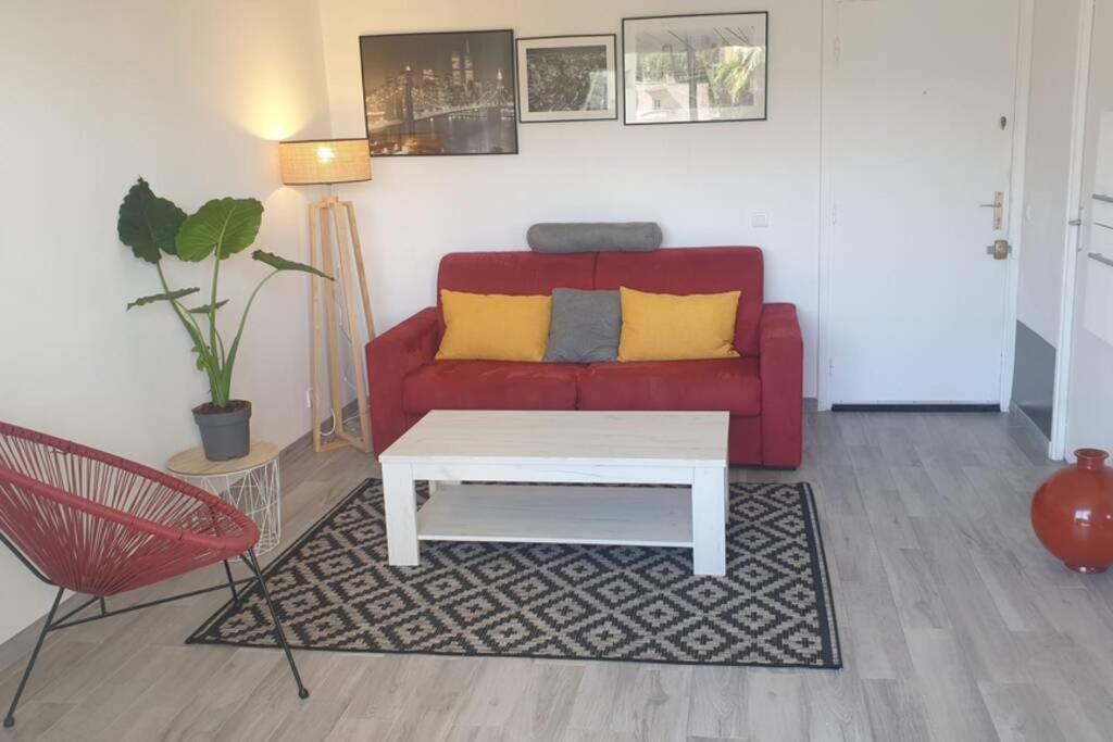 a living room with a red couch and a coffee table at AiguesMarines in Cagnes-sur-Mer