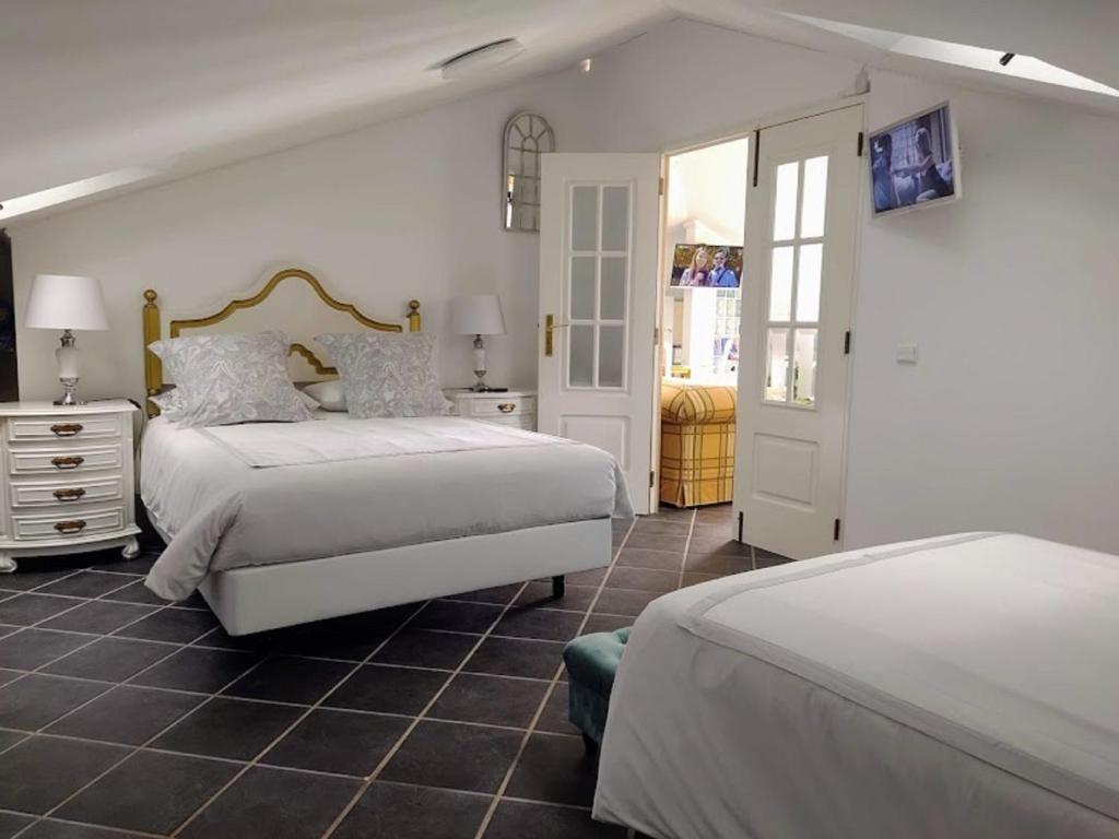 a white bedroom with two beds and a doorway at ATTIC BAY in Câmara de Lobos