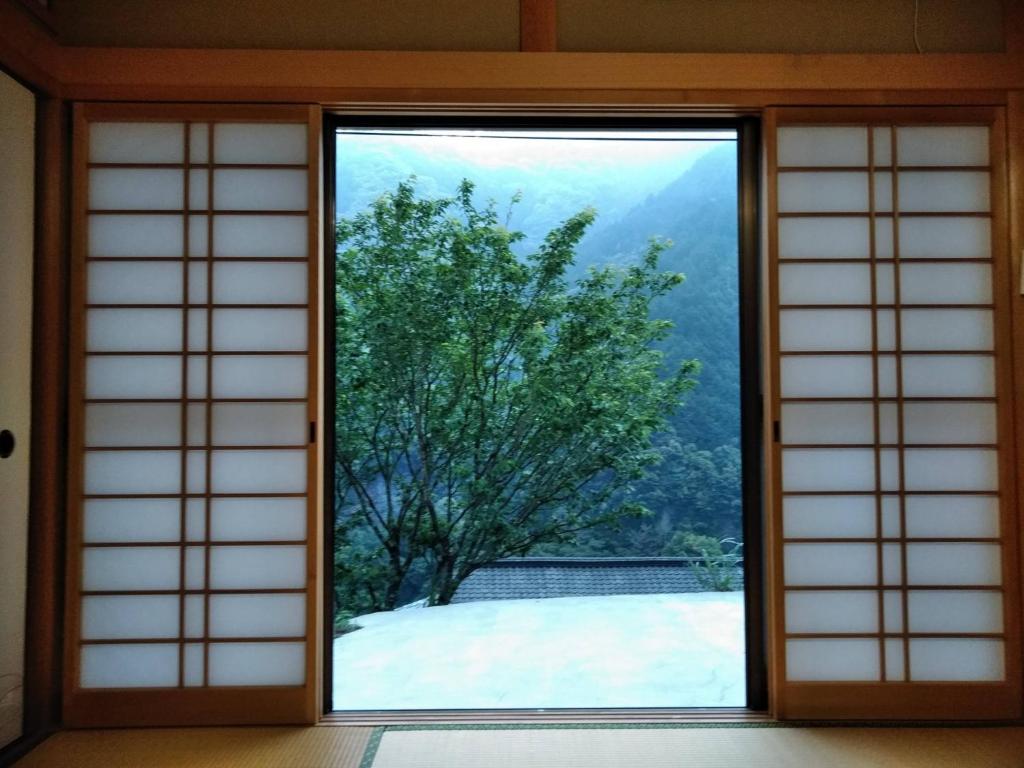 eine offene Tür mit Blick auf einen Baum in der Unterkunft Satoyama no Yado Kei-House - Vacation STAY 55796v in Shikokuchuo
