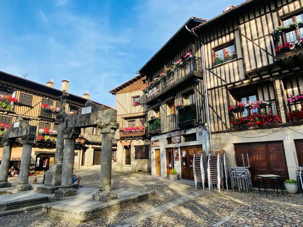 un ancien bâtiment avec des tables et des chaises dans une cour dans l'établissement Hostal La Alberca, à La Alberca