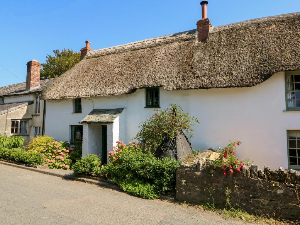 a white cottage with a thatched roof at Bell Buoy Cottage in Bude