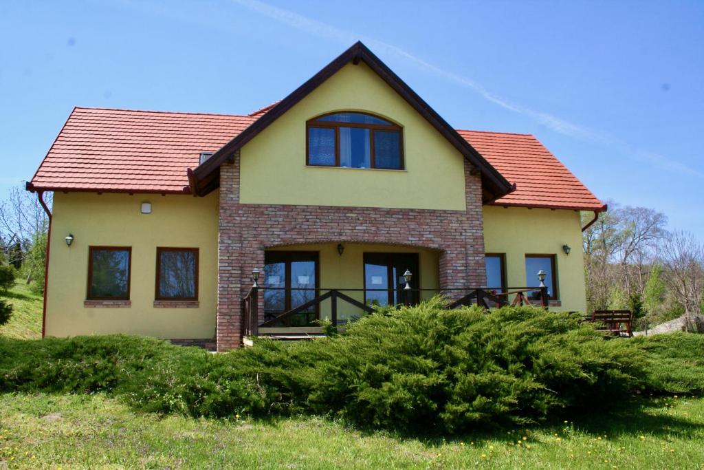 una casa con techo rojo en un campo verde en Villa Vinea, en Etyek
