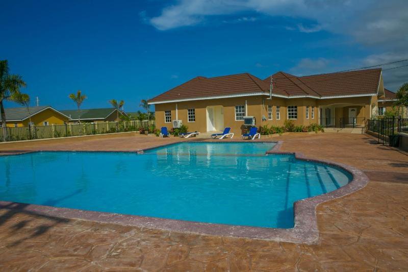 a house with a swimming pool in front of a house at Ochi Rios ApartHotel by JHH in Ocho Rios