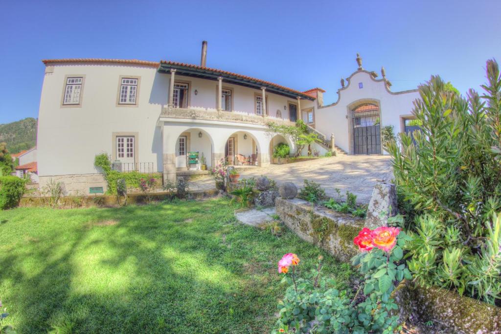 a large white house with a yard with flowers at Quinta de São Roque in Vila Nova de Cerveira