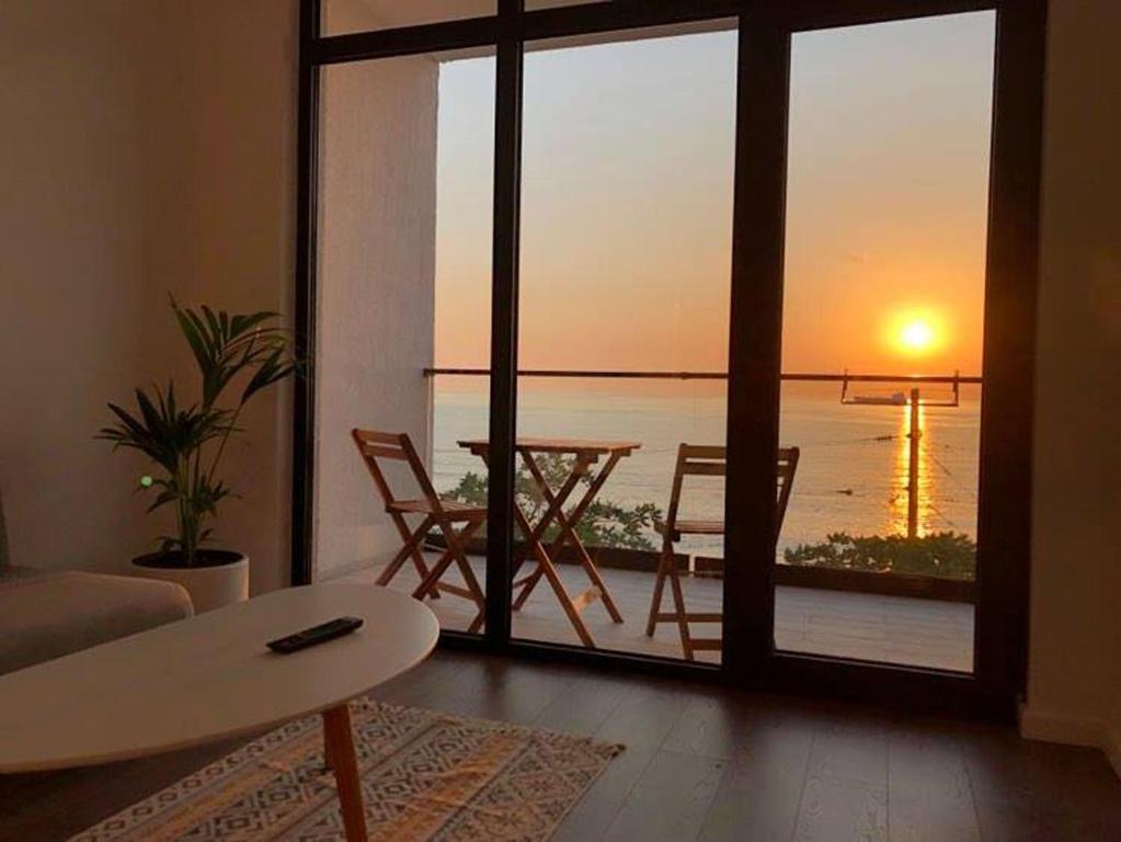 een woonkamer met een tafel en uitzicht op de oceaan bij Cabo Verde Boutique Hotel in Batoemi