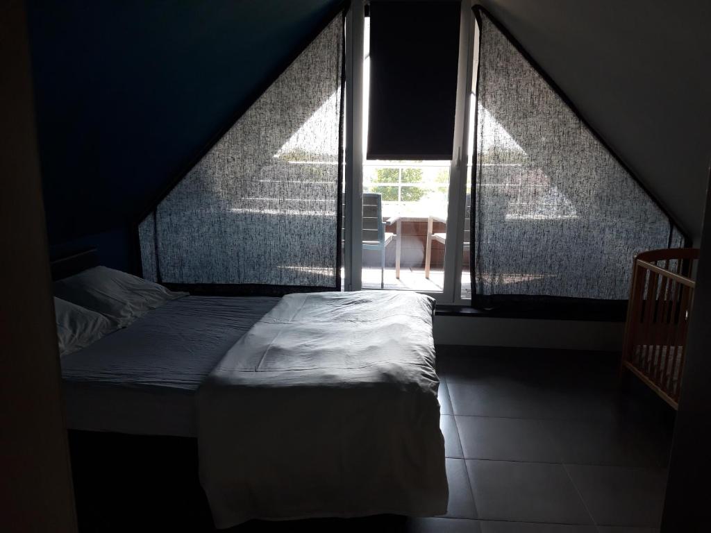 - un lit dans une chambre avec fenêtre dans l'établissement Duplex met zwembad Neoportus, à Nieuport