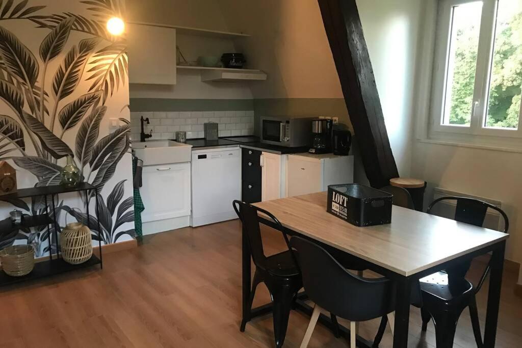 a kitchen with a wooden table and a table and chairs at El Castillo, aux portes de Honfleur in Gonneville-sur-Honfleur